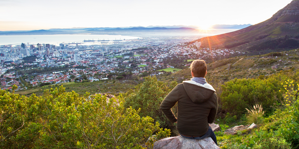 Young man on hillside overlooking a coastal city